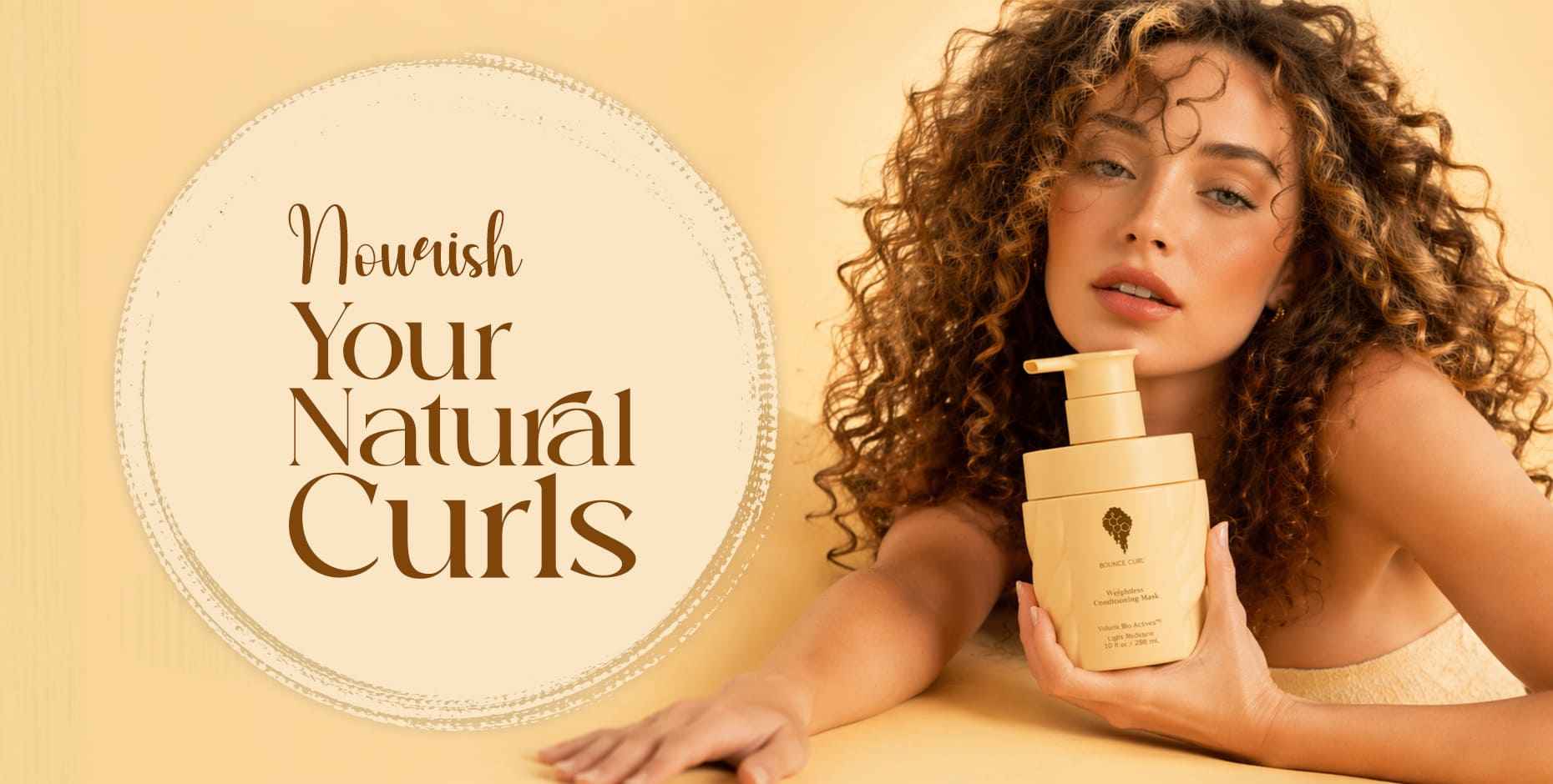 Woman with voluminous, defined natural curls holding a Bounce Curl conditioning mask.