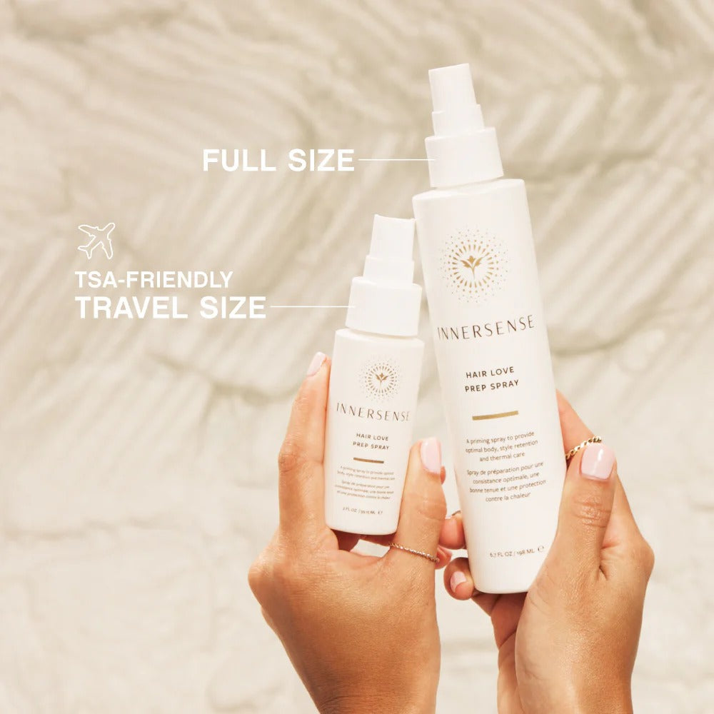 Hands holding Innersense Hair Love Prep Spray: full-size white bottle and TSA-friendly travel size.