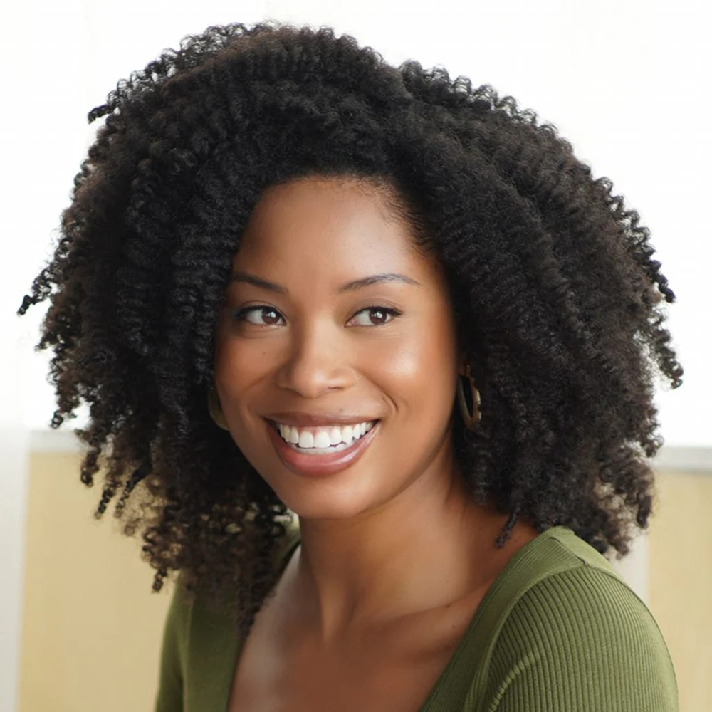 Smiling woman with voluminous, dark curly hair and a green top.