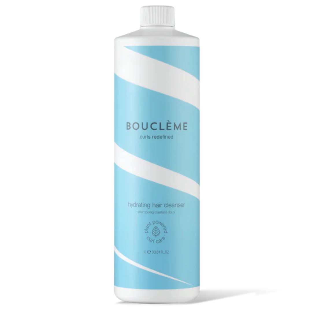Bouclème Hydrating Hair Cleanser in a large white bottle with light blue wavy stripes and text.