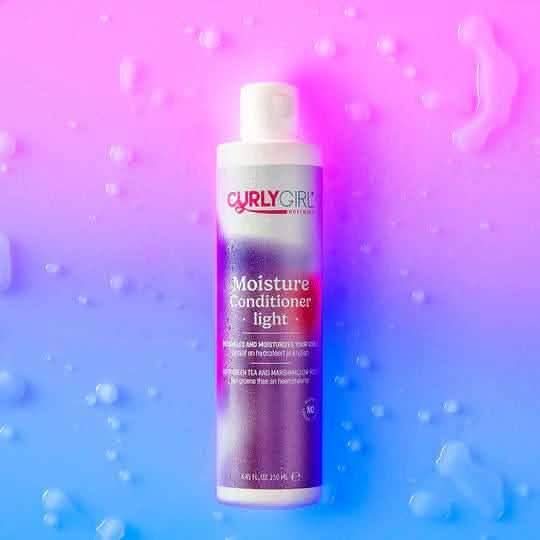 White Curly Girl Movement Moisture Conditioner Light 250ml bottle with purple and pink label on a wet blue and pink background.