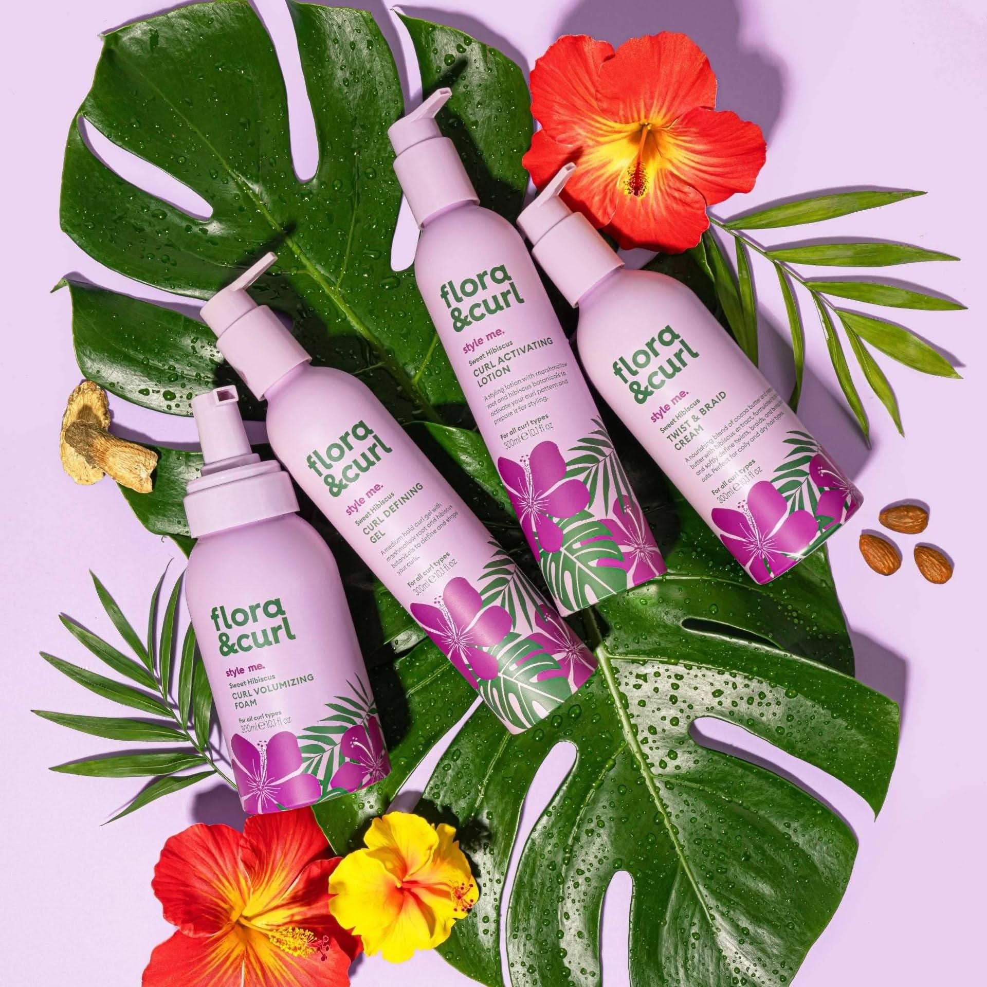 Four Flora & Curl lavender bottles with hibiscus designs, tropical leaves, and red/yellow flowers.